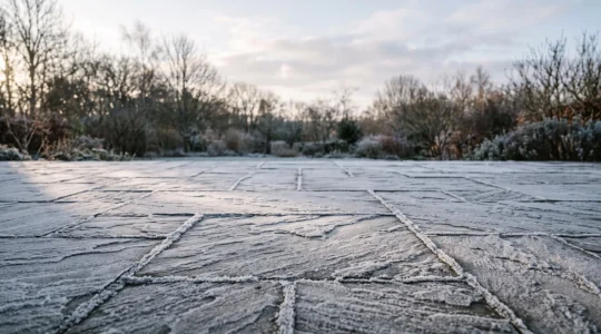 Terrasse en dallage de pierre naturelle recouverte de givre matinal en hiver, illustrant la resistance au gel