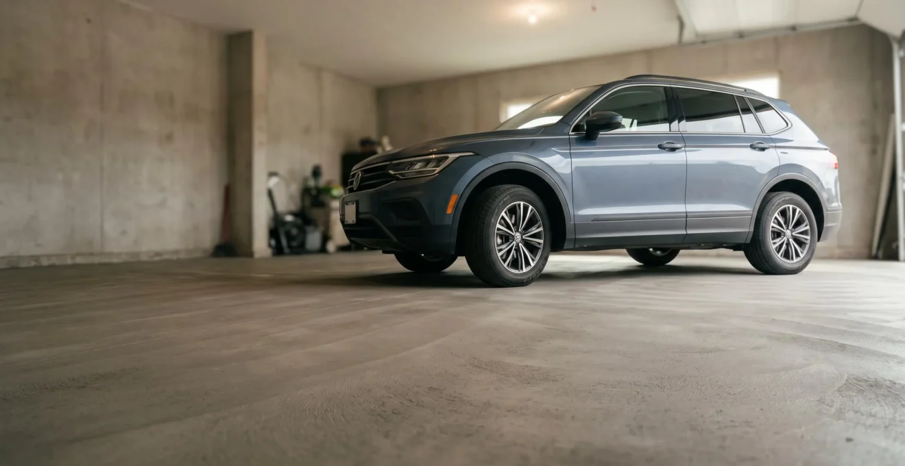 SUV garé sur une dalle de béton neuve et lisse dans un garage résidentiel, illustrant la robustesse du sol face à une charge lourde